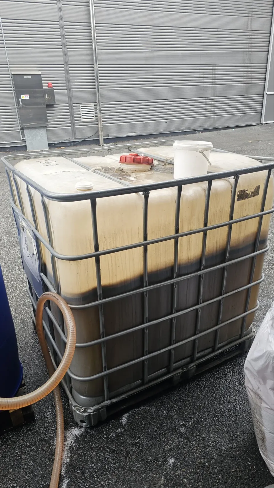 야외에 놓인 대형 약제 용기(IBC)와 연결된 이송 호스